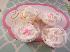 three cupcakes with white frosting and pink sprinkles in plastic cups