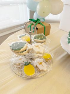 some cookies are sitting on a table near a box with balloons and a gift bag