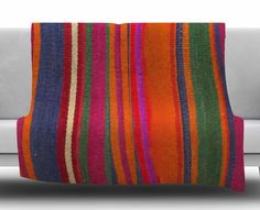 an orange and purple striped blanket sitting on top of a couch next to a white sofa