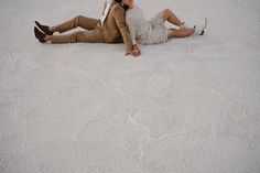 a man and woman are laying on the ground in their wedding attire, smiling at each other