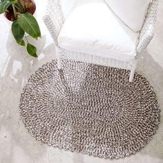 a white chair sitting on top of a rug next to a potted plant