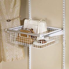 a white wire basket hanging on the wall next to a closet door with purses and handbags in it