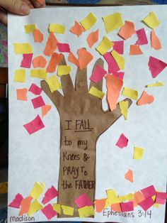 a child's hand holding up a tree made out of paper