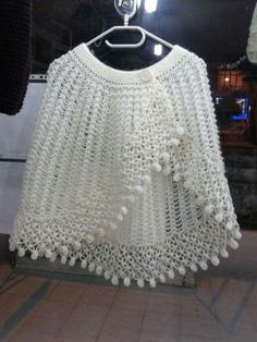 a white crocheted sweater hanging on a rack