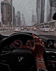 a person driving a car in the rain with their hands on the steering wheel and dashboard