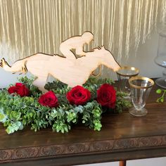 a wooden horse with red roses and greenery