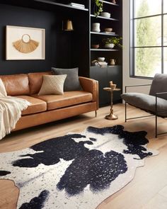 a living room filled with furniture and a cow rug on top of a hard wood floor