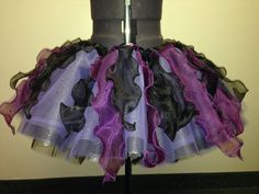 a purple and black dress on a mannequin headdress in front of a wall