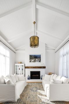 a living room with white couches and a rug on the floor in front of a fireplace