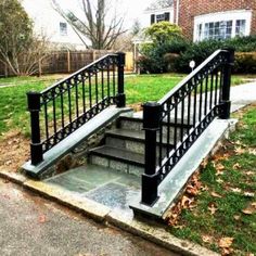 an outdoor stair case with wrought iron railing and handrails in front of a brick house