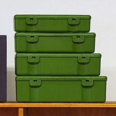 four green storage boxes sitting on top of a wooden shelf next to a purple box