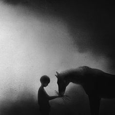 a man standing next to a horse in the fog with it's head down