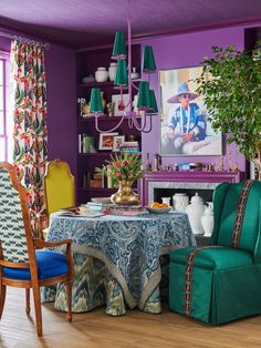 a dining room with purple walls and green chairs, blue table cloth on the table