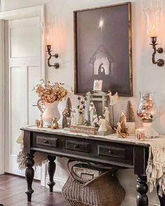 a black table topped with lots of vases filled with flowers and other items next to a painting