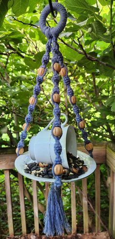 a blue bird feeder hanging from a tree