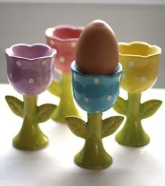 four different colored eggs sitting on top of each other in small cups with polka dot designs