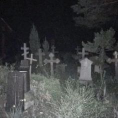 a cemetery with tombstones and crosses in the grass at night, all lit up