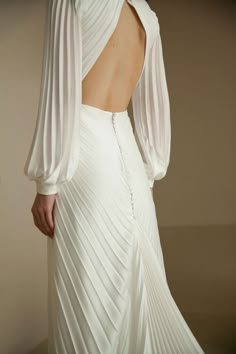 the back of a woman's white dress with pleated sleeves and open shoulders