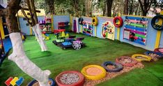 an indoor play area with lots of toys on the ground and trees in the background