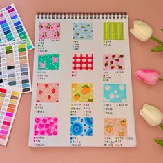 an open notebook with different patterns on it next to tulips and other flowers