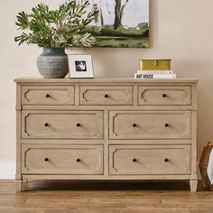 a white dresser with drawers and pictures on top