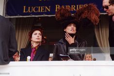 two women and one man are looking out the window at an event while others look on