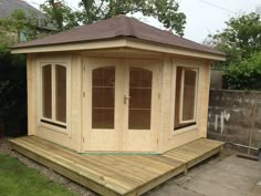 a wooden gazebo sitting on top of a lush green field