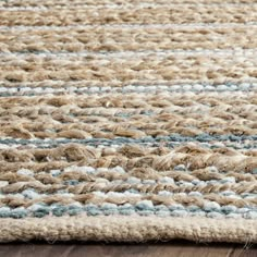 an area rug with blue and white stripes on the top is laying on a wooden floor