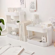 a white desk topped with lots of books and other office supplies on top of it