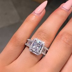 a woman's hand with two engagement rings on it and the ring is surrounded by diamonds