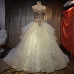 a wedding dress is displayed on a mannequin in front of a red curtain