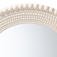 an oval mirror with white beads on it