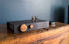 a black amplifier sitting on top of a wooden table next to a wall with blue walls