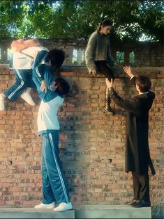 two men standing on top of a brick wall next to another man in a suit