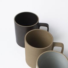 three coffee mugs sitting next to each other on a white surface with no one around them