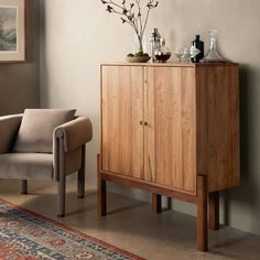 a wooden cabinet sitting next to a chair in a living room