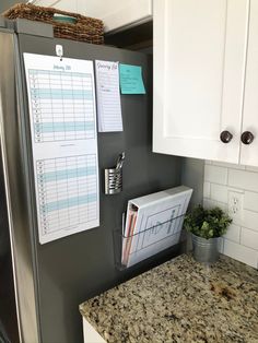 a refrigerator with magnets and papers on it in a kitchen next to white cabinets