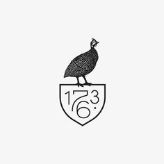 a bird sitting on top of a shield with the number seventy written in black ink