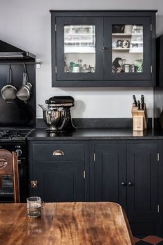 a kitchen with black cabinets and silver appliances on the counter top, along with a wooden cutting board