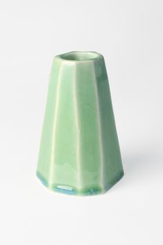 a green vase sitting on top of a white table