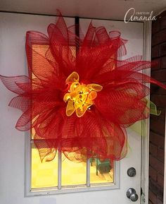 a red mesh flower is hanging on the front door to decorate it's entrance