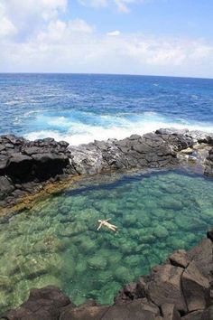 a person swimming in the ocean near rocks