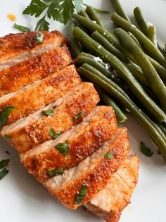 some meat and green beans on a white plate