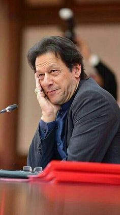 a man sitting at a table with his hand on his face while looking off to the side