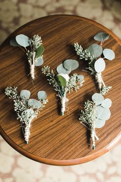 flowers and greenery are arranged on a wooden table in order to be used as centerpieces