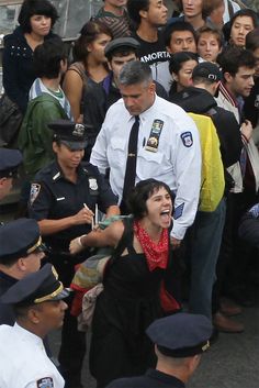 a group of people standing around each other in front of a police officer with his mouth open