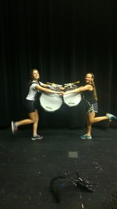 two young women are dancing with their drums