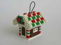 a small christmas ornament made to look like a gingerbread house with red, green and white decorations