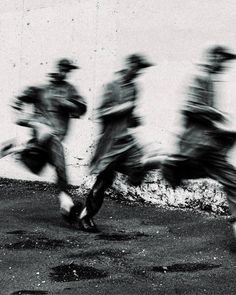 black and white photograph of people running in the street with blurry image behind them