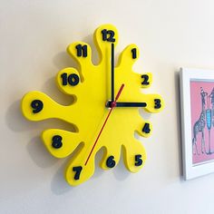 a yellow clock on the wall with numbers and giraffes